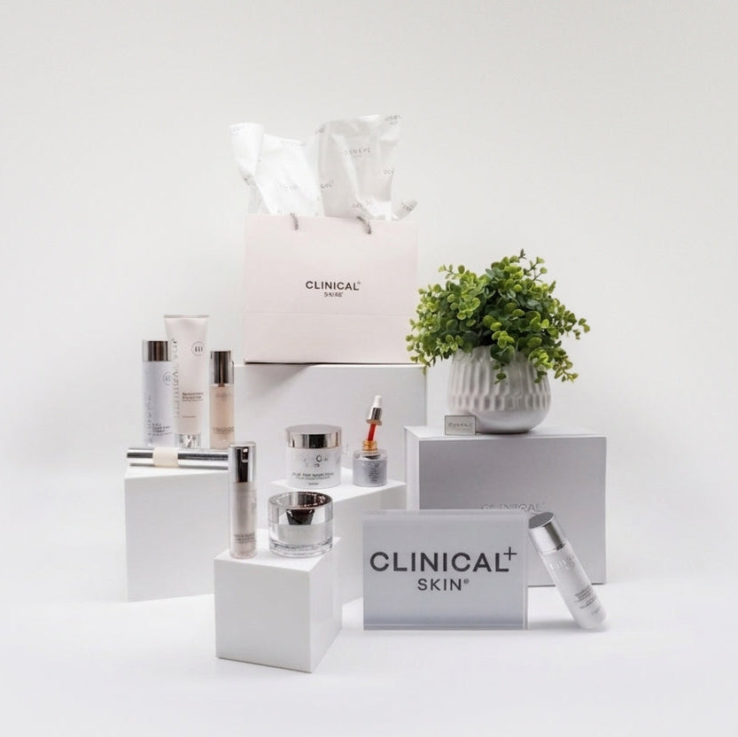 Clinical Skin Oil Control Reset Routine – complete oil control skincare set with Clinical Skin serums, moisturizer, and cleanser on white platforms with branded shopping bag on gray background