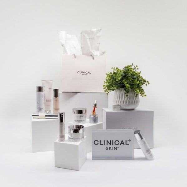Clinical Skin Oil Control Reset Routine – complete oil control skincare set with Clinical Skin serums, moisturizer, and cleanser on white platforms with branded shopping bag on gray background