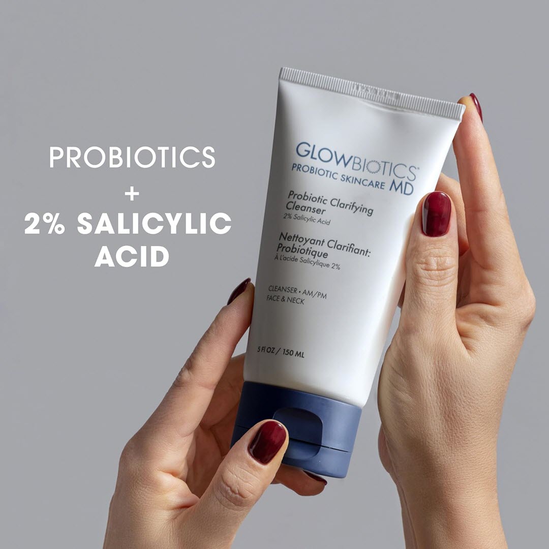 Woman holding a tube of Glowbiotics Probiotic Clarifying Cleanser, formulated with probiotics and 2% salicylic acid