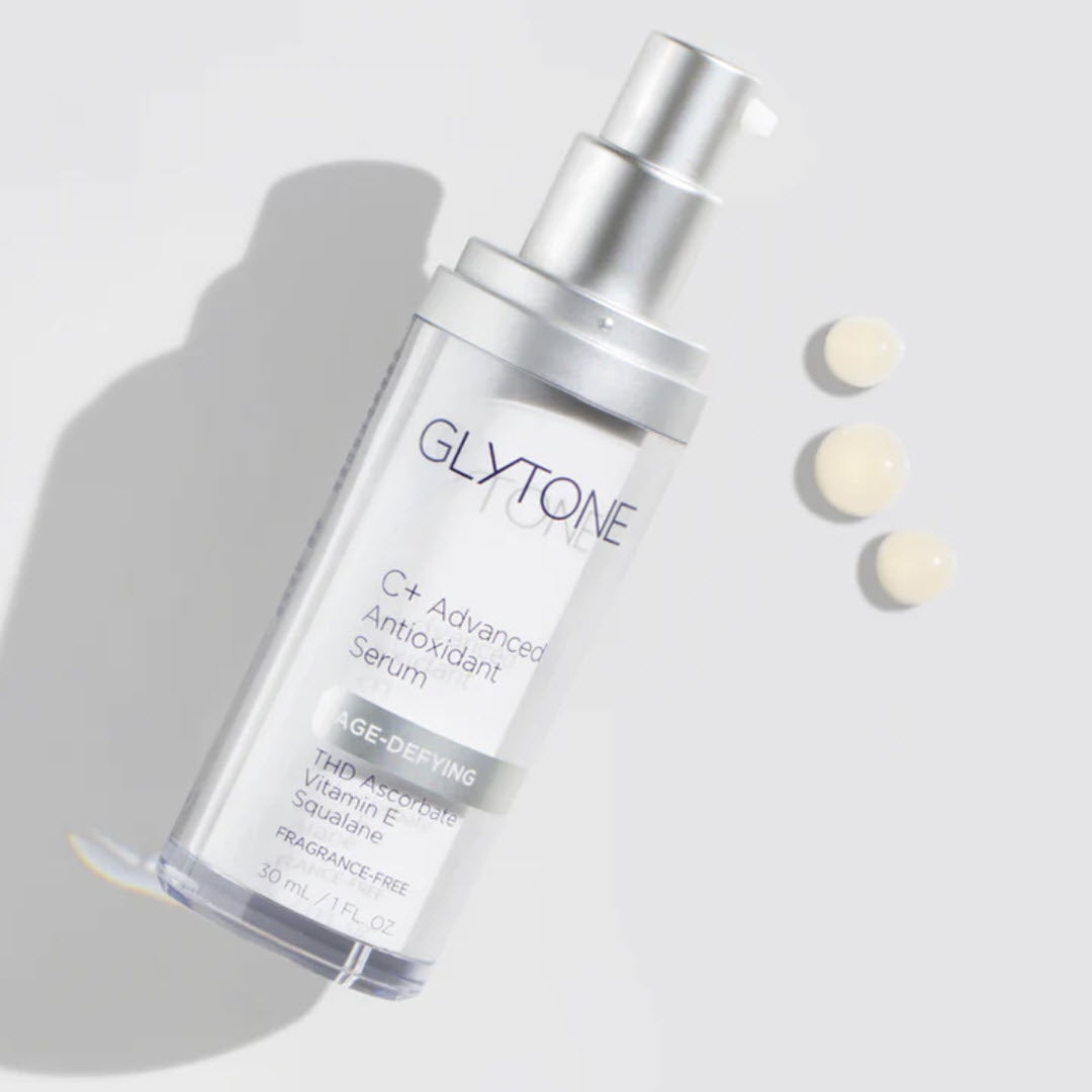 Glytone Age-Defying C+ Advanced Antioxidant Serum lightweight texture shown beside bottle with THD ascorbate vitamin C complex