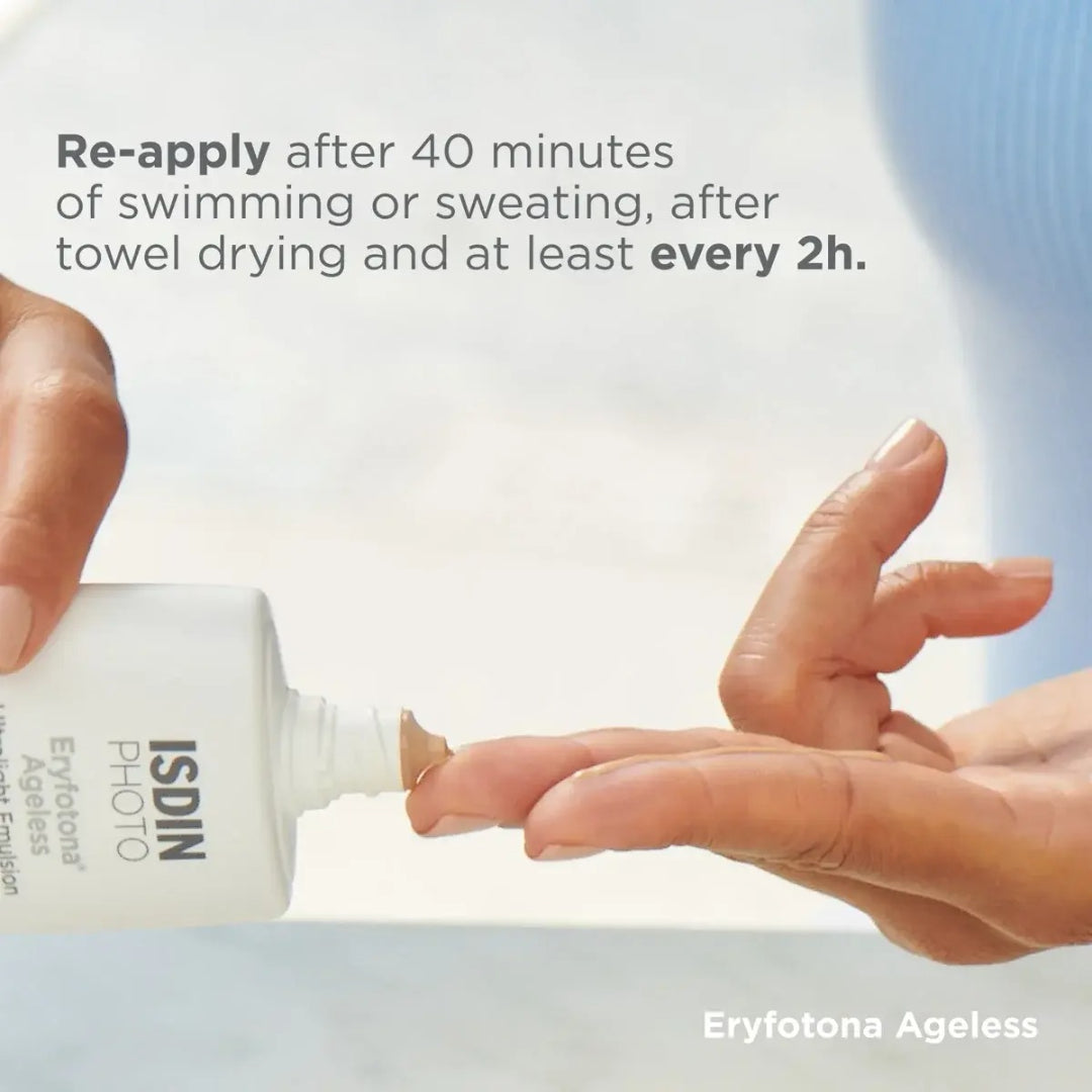 Hand applying ISDIN Eryfotona Ageless sunscreen to fingers with instructions reapply after 40 minutes of swimming or sweating after towel drying and at least every 2 hours