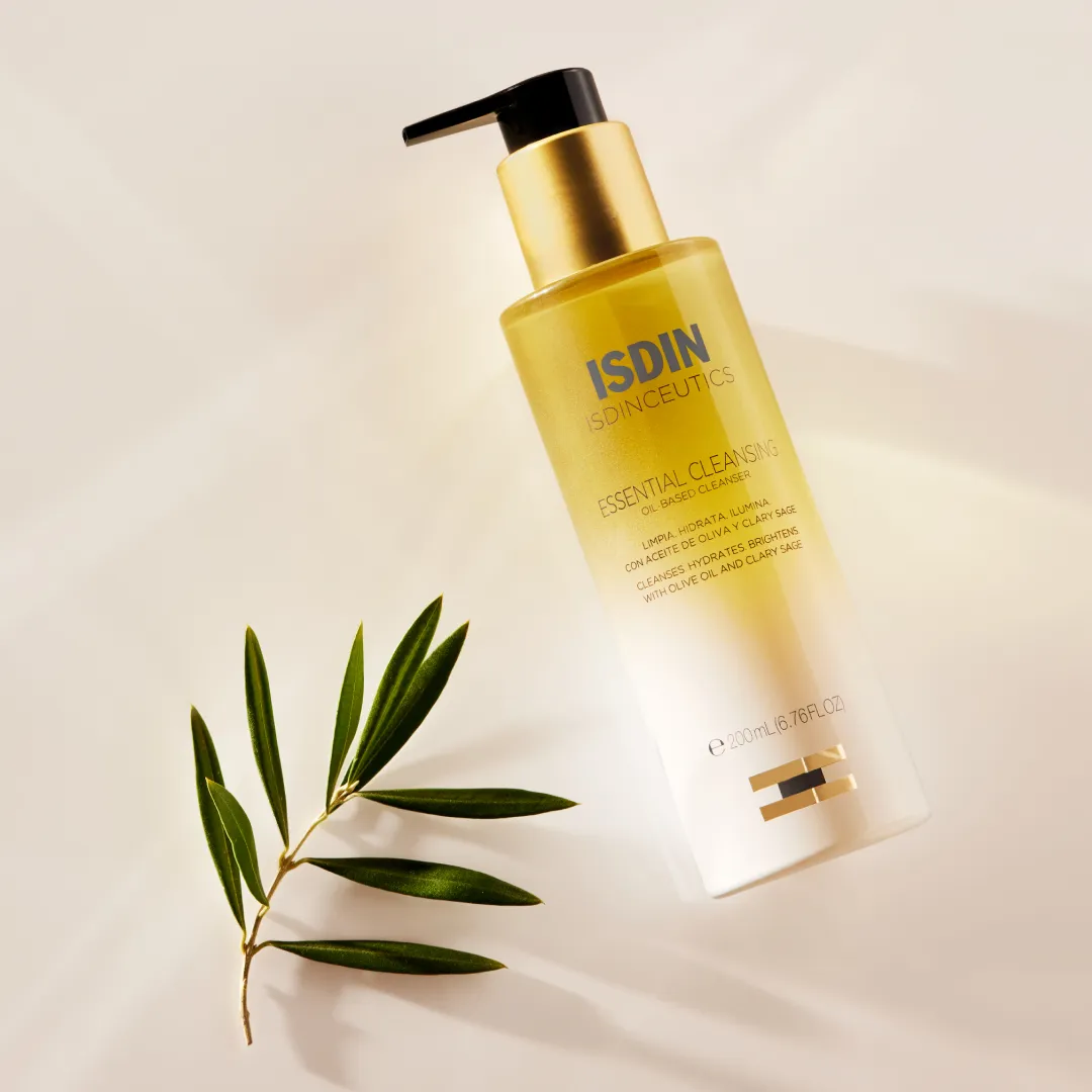 ISDIN Essential Cleansing bottle beside olive branch sprig