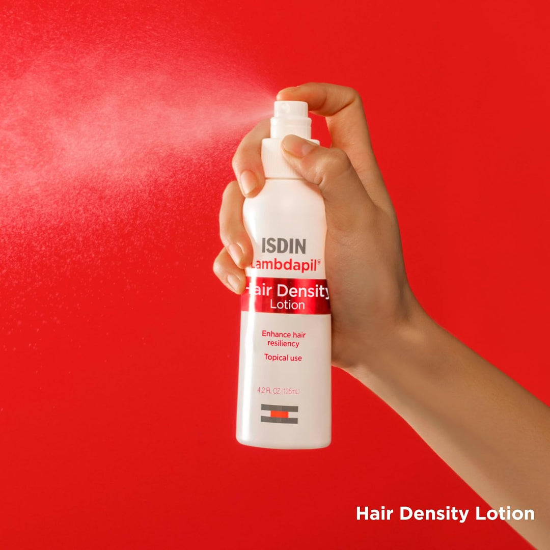 Hand spraying ISDIN Lambdapil Hair Density Lotion against red background with text hair density lotion