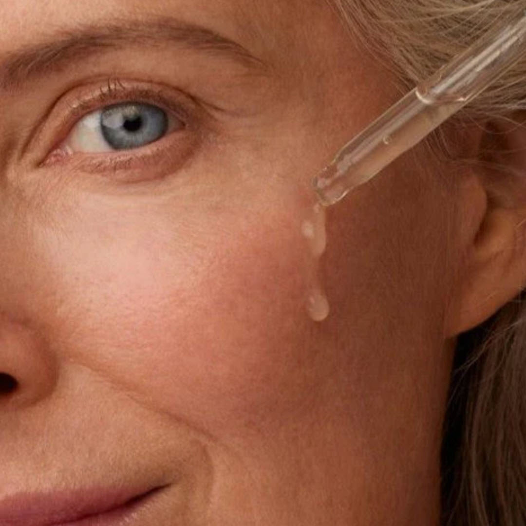 Close-up of a dropper applying Luzern Serum Absolut Firming Collagen Booster near a woman's eye