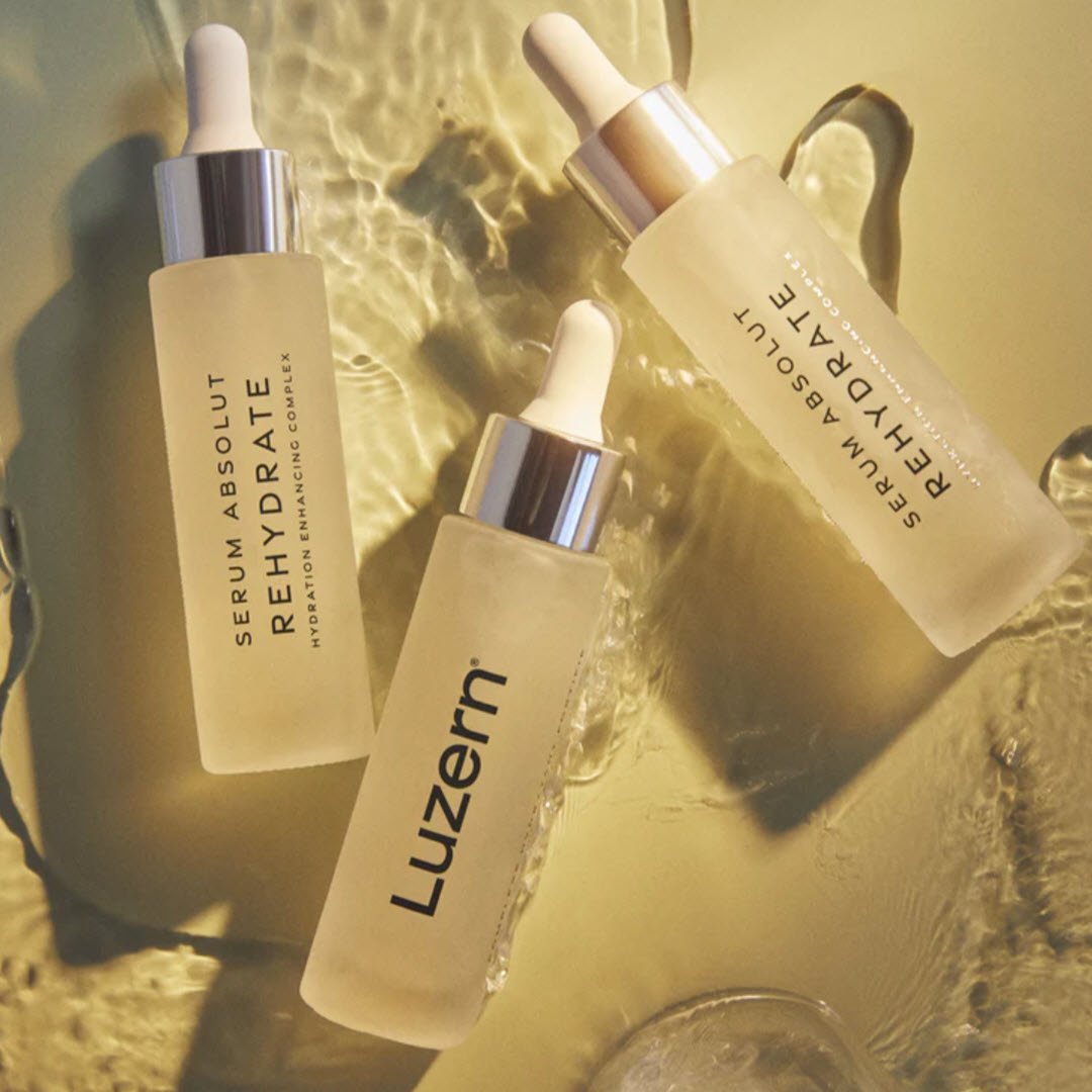 Three bottles of Luzern Serum Absolut Rehydrate Hydration Enhancing Complex styled in golden water