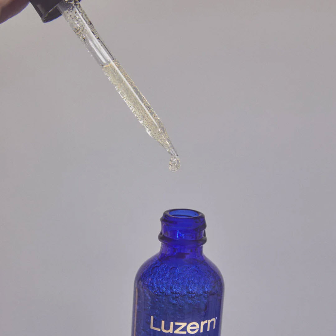 Dropper of Luzern Serum Absolut V15+ Vitamin C and Ferulic Serum above the open bottle