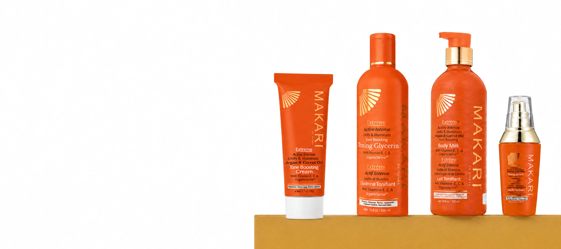 Four MAKARI sun care products in orange packaging arranged on a tan platform against a white background, including a body lotion tube, body lotion pump bottle, and two smaller bottles.