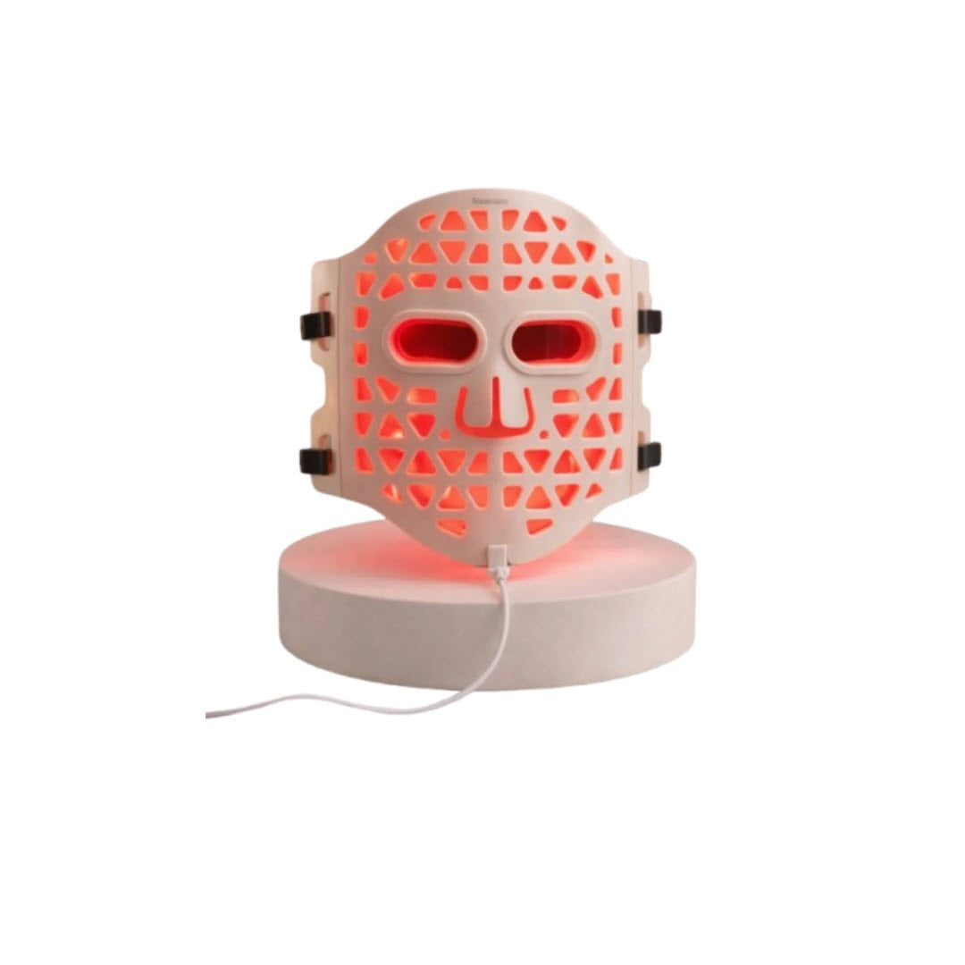 Numiere Feather LED Face Mask on charging stand, glowing red light therapy