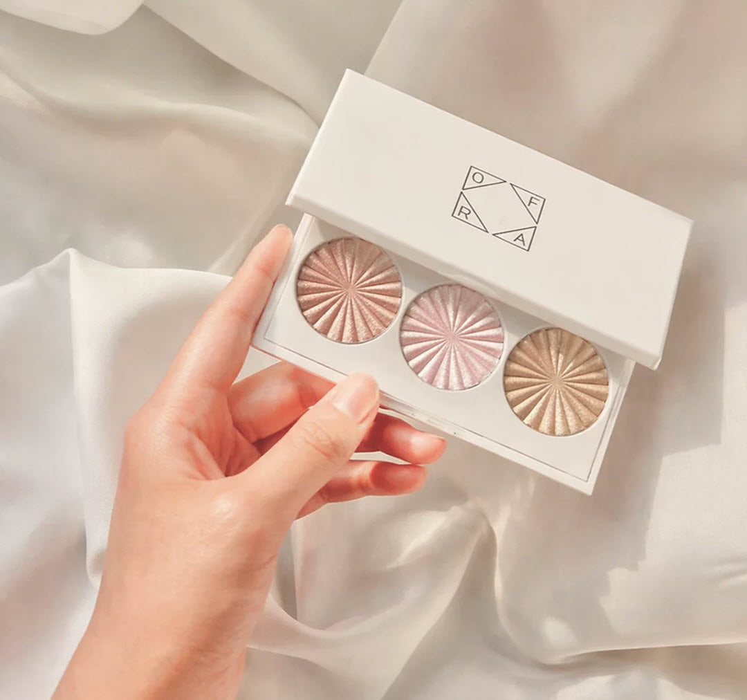 Hand holding the open OFRA Cosmetics Feelin' Myself Highlighter Palette showing all three shades
