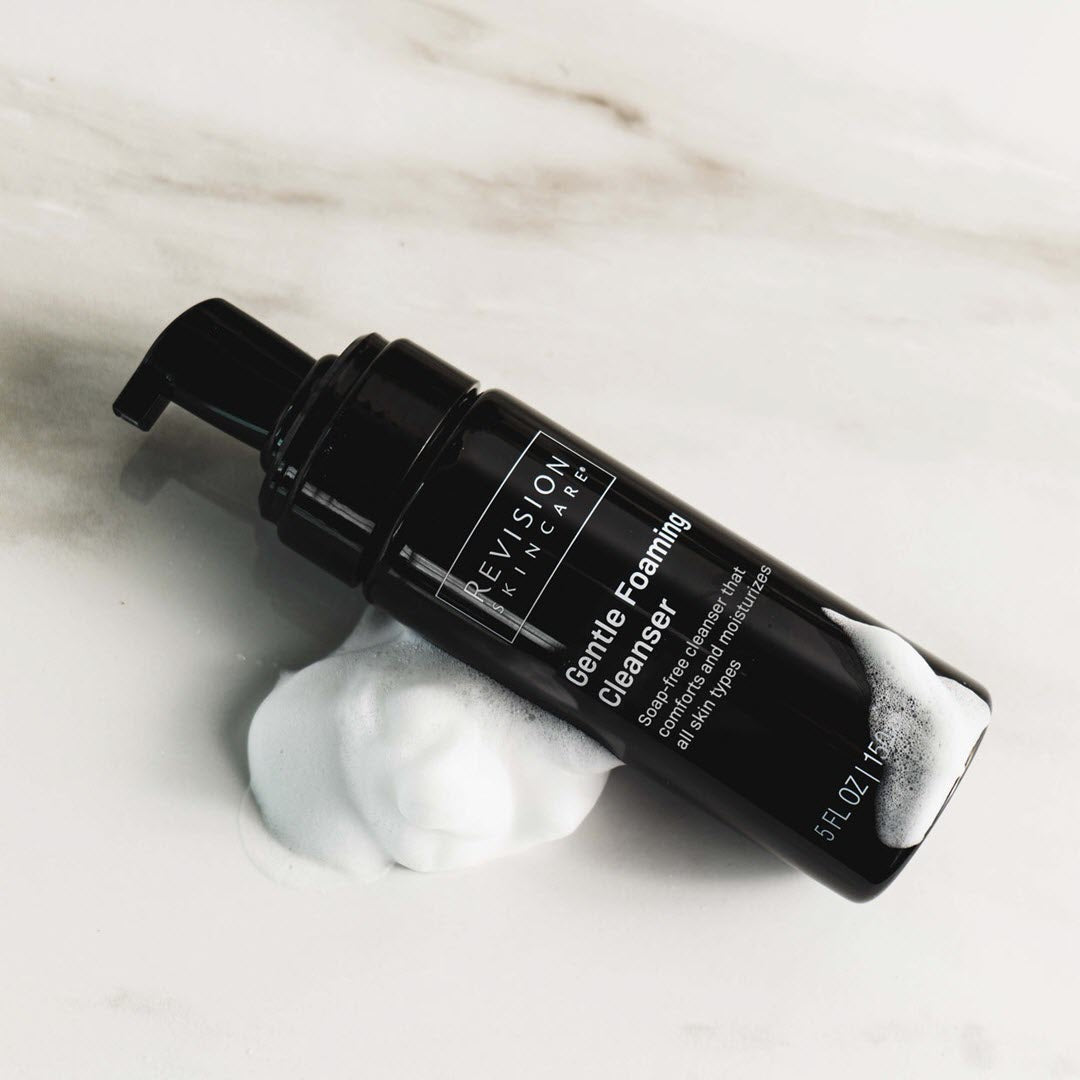 Revision Skincare Gentle Foaming Cleanser 5 FL OZ bottle on marble with foam texture