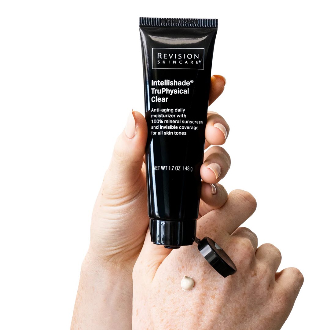 Revision Skincare Intellishade TruPhysical Clear tube held in hand with product dispensed