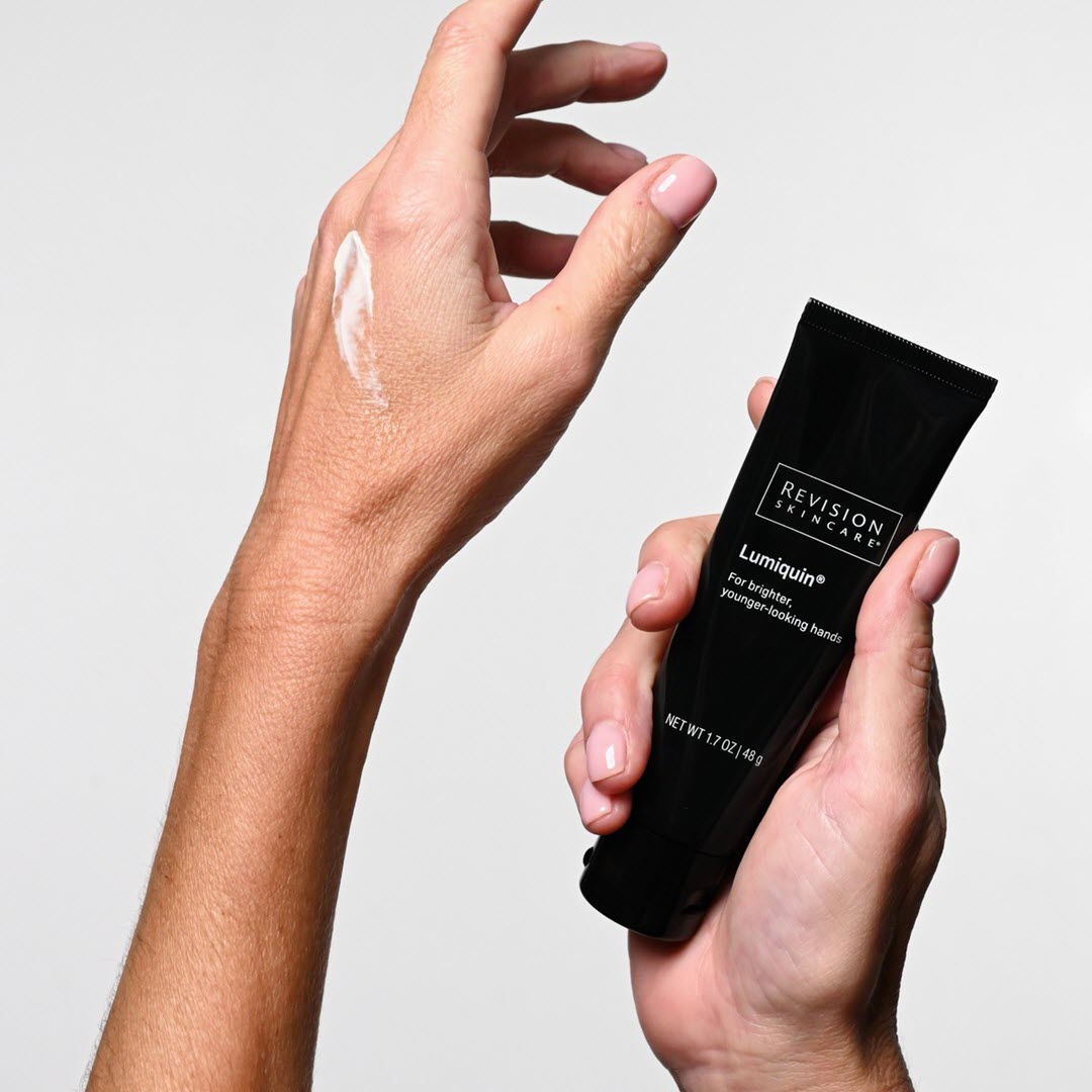 Revision Skincare Lumiquin 1.7 oz tube held in hand with cream applied to skin