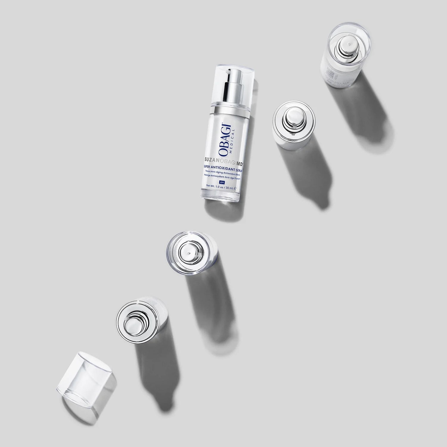 Obagi SuzanObagiMD Super Antioxidant Serum pump bottle with disassembled cap components arranged diagonally on gray background