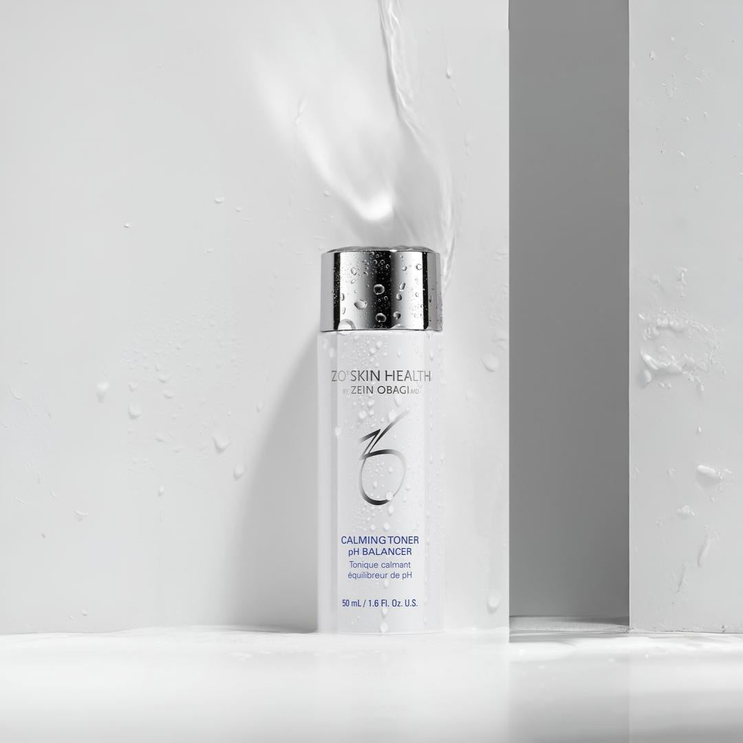 ZO Skin Health Calming Toner pH Balancer bottle with water droplets and splash against gray geometric background – refreshing pH-balancing toner