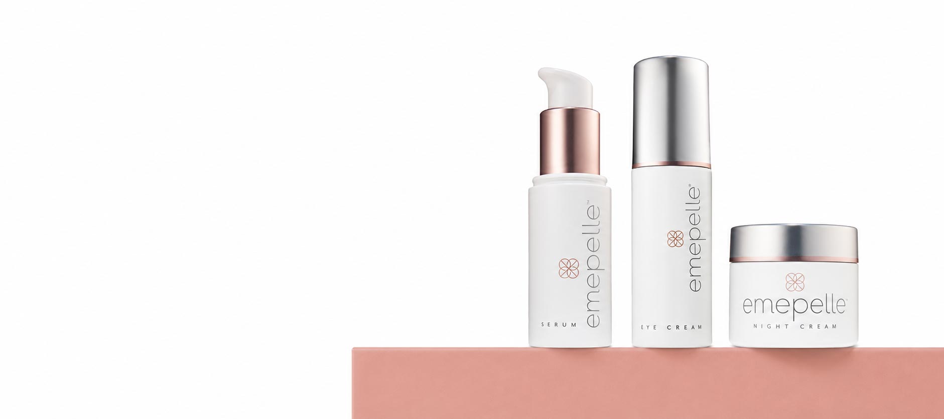 Three emepelle skincare bottles and a jar arranged on a pink platform against a white background.