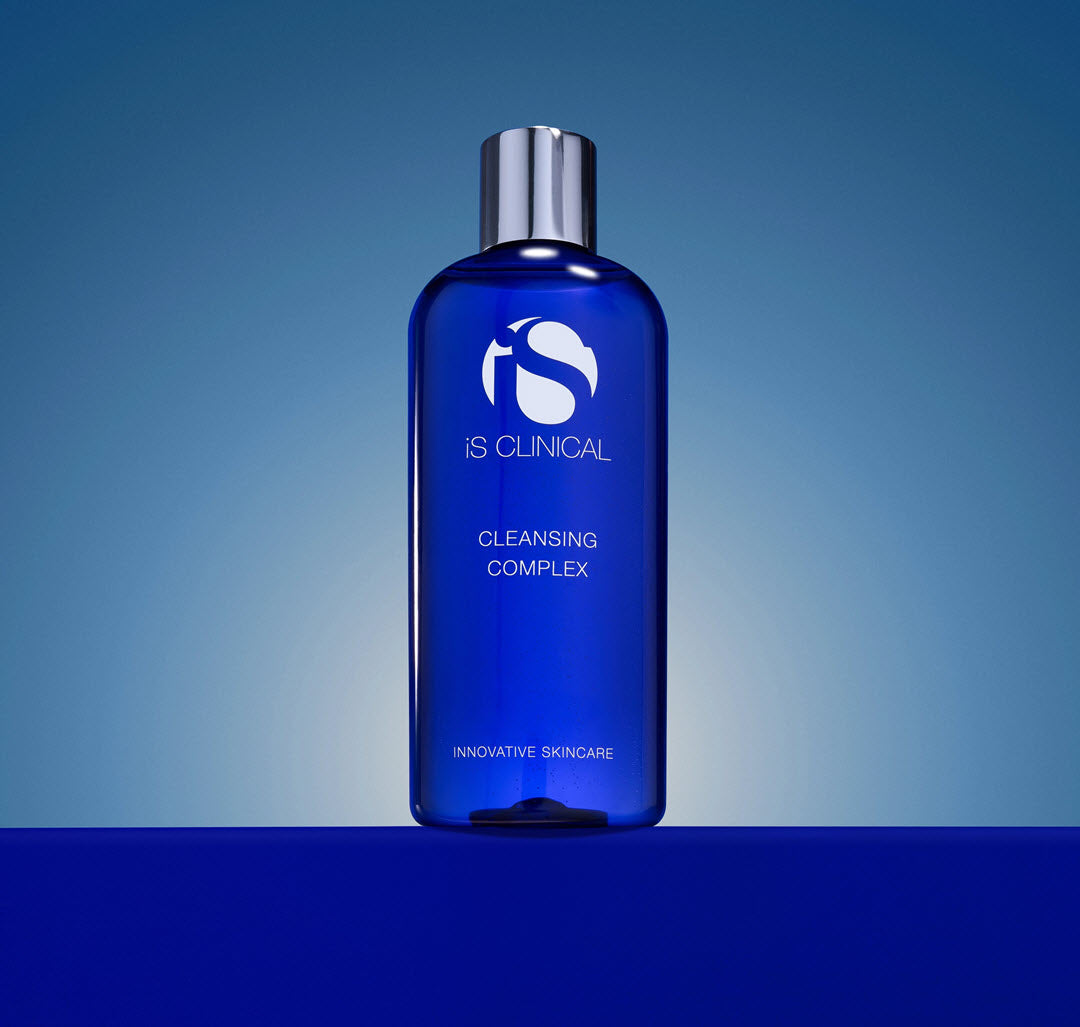 iS Clinical Cleansing Complex bottle on a blue gradient background