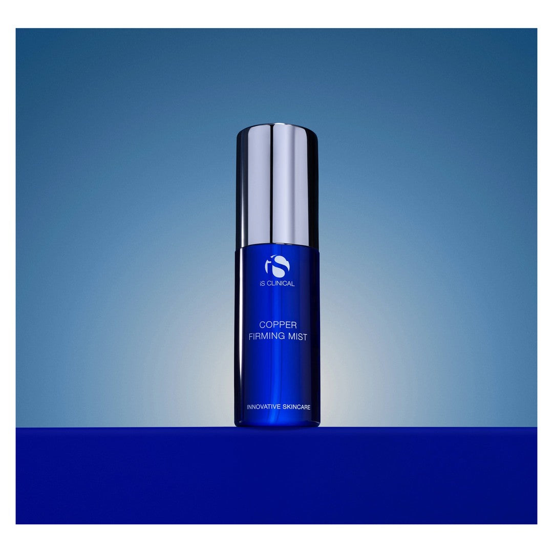 iS Clinical Copper Firming Mist bottle on a blue gradient background
